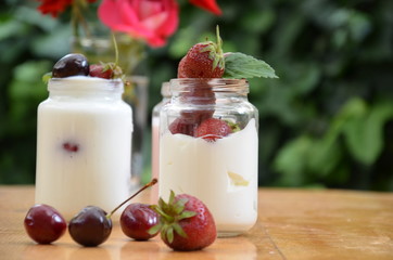 Healthy breakfast home made pudding or yogurt or granola, strawberries, cherry, berry,  yogurt in a bowl. Vegetarian concept food. pudding or cocktail on of green foliage