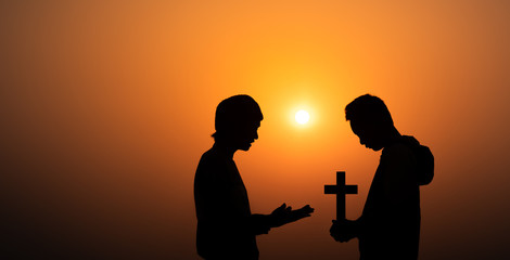 Young christian sharing the Gospel to boy in morning with sun light background, christian silhouette concept.