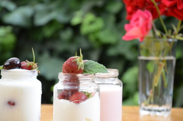 Healthy breakfast home made pudding or yogurt or granola, strawberries, cherry, honeysuckle berry, nuts and yogurt. Vegetarian concept food. pudding or cocktail on the background of green foliage