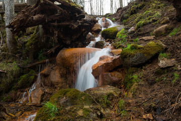 City Cesis, Latvia. Old waterfall with green moss and red rocks.