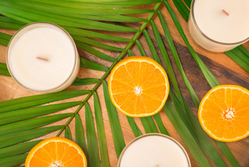 White candles and oranges on a wooden tray with palm leaf