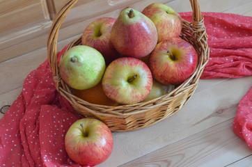 Fresh fruit on a wooden background. Straw basket with apples and pears. Autumn harvest in season. Thanksgiving day