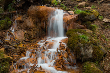 Fototapeta na wymiar City Cesis, Latvia. Old waterfall with green moss and red rocks.