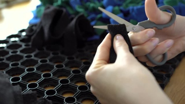 Cutting green, blue and black fleece fabric stripes into same length. Making dog snuffle mat. Fun Mental Stimulation Nose Work for pets. Nose work for pets. Preparing dog nosemat.
