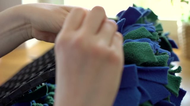 Making dog snuffle mat from green, blue and black fleece fabric stripes. Fun Mental Stimulation Nose Work for pets. Cognitive stimulation for pup. Nose work for pets. Preparing dog nosemat.