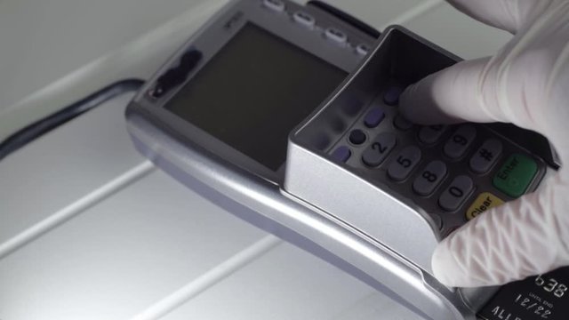 Hand wearing hygienic gloves using pdq payment machine medium shot