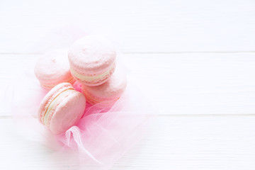 Pink macaroons on white wooden board. French cookies, sweets background