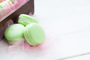 Green macaroons on white wooden board. French cookies, sweets background
