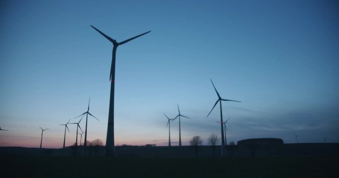 Many wind turbines rotating in the evening.