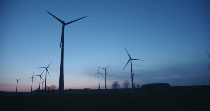 Many wind turbines rotating in the evening.