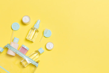 Set of travel size cosmetic bottles on yellow background. Flat lay of cream jars. Top view of bodycare style concept