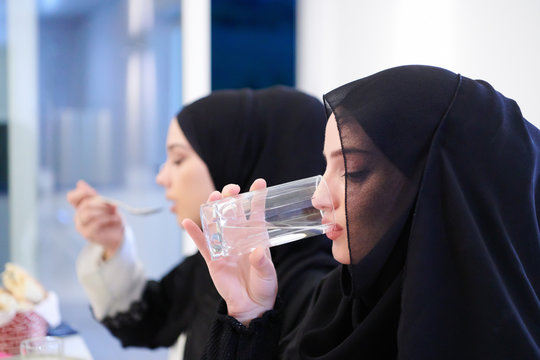 Muslim family having Iftar dinner drinking water to break feast