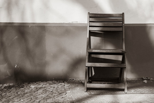 An empty chair standing in front of a house wall, black and white photo