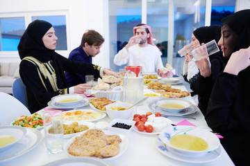Muslim family having Iftar dinner drinking water to break feast