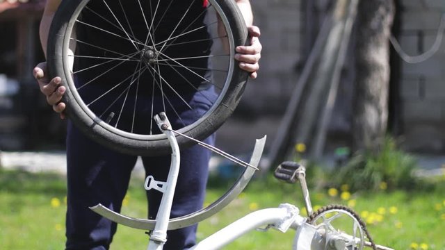 Fixing a bike. Bicycle repair. Person taking out a bike wheel of an old bicycle.