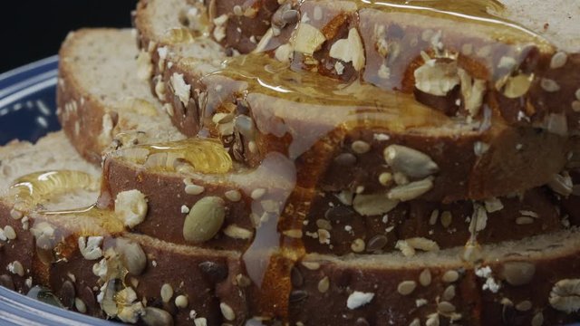 Honey dripping on top of multi grain bread in slow motion dolly in.