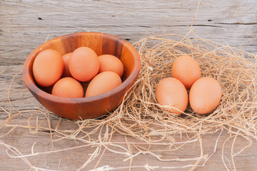Fresh chicken eggs from the farm are put in a wooden cup and then on the wooden floor.