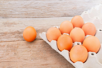 Close-up view of raw chicken eggs in egg box on wooden background.