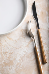 Creative background consisting of a ceramic empty plate, with a kitchen towel on a beige background.