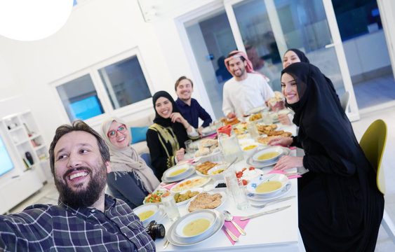 Muslim family having Iftar dinner taking pictures with mobile phone