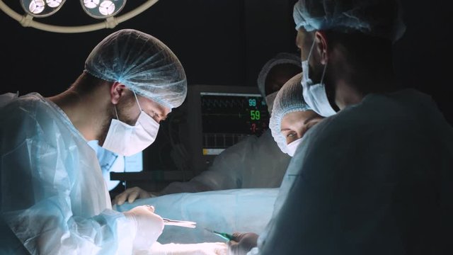 An international team of doctors performs a complex surgical operation on a patient under anesthesia. Modern operating room and experienced surgeons save lives