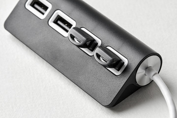 Black portable USB hub for four connections with usb flash drives on a white background. Bus povered. Closeup, selective focus