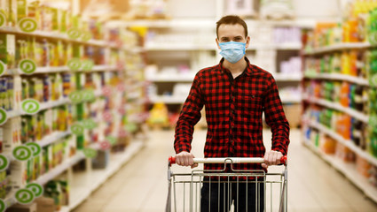 Man in protective mask shopping in supermarket pushing trolley during epidemic