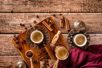 Top down view of coffee cups, beans and spices on a wood coffee table