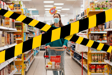 Do not cross.Barrier tape - quarantine, isolation.A young woman with a medical mask on her face, rolls a grocery cart through the store. The concept of shopping and protecting against the coronovirus
