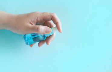 Human hand use antiseptic  spray for  disinfection .Prevent  infection coronavirus COVID-19. Female hand applying alcohol spray  on blue background