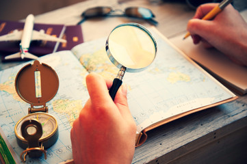Young woman planning her vacation with travel map. She's looking for next destination with...
