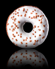 Glazed donut with sprinkles on a black background rotated in three quarters