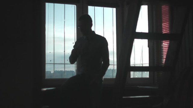 An Adult Man Drinks Coffee  While He Quarantined at Dark Apartment in the Morning.