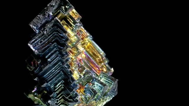 Amazing colorful rainbow Bismuth Gemstone macro closeup isolated on black background.