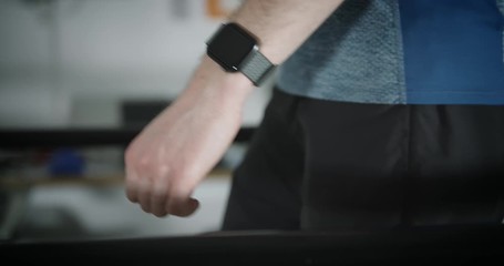 Male caucasian walking on treadmill in slow motion with smartwatch - Powered by Adobe