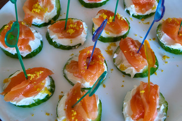 Red fish sandwiches with soft cheese and fresh cucumber on a white plate