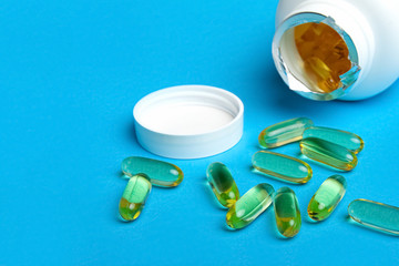 Transparent yellow drug capsules spilled from a can. On a blue background. Vitamins Biologically active food additives.