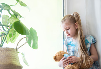 Sad child girl by the window