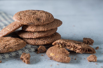 Stacked delicious crunchy homemade chocolate cookies crumble with on top of cloth napkin, marble table with dark background. Rustic concept
