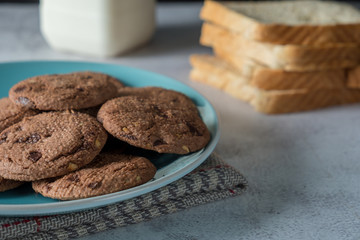 Fototapeta premium Delicious crunchy homemade chocolate cookies on a plate with cloth napkin, marble table with dark background. Rustic breakfast concept