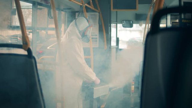 Male worker disinfects a bus from inside to kill virus. Disinfect, disinfection concept.