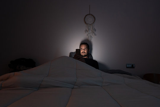 hombre mirando al movil en la cama men looking at the phone in bed covid19