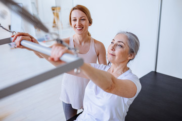 Pilates aerobic female instructor workout with fit man in cadillac fitness exercise. Active and healthy lifestyle rehabilitation concept.