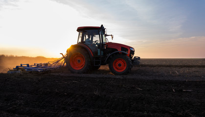 Obraz premium Tractor is preparing the land at dusk