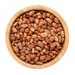 Dried pinto bean in wooden bowl isolated on white. Top view.