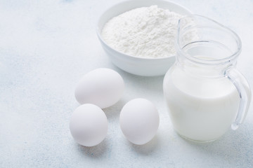 Milk, flour and eggs on a white background. Ingredients for pie. Recipe