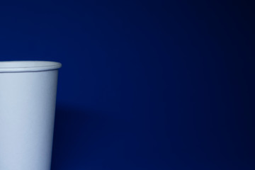 An empty white paper cup on a blue background