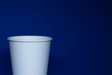 An empty white paper cup on a blue background