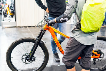 Young man with a yellow backpack stands and holds a bicycle