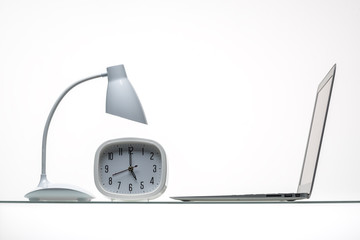 table lamp with computer mouse and laptop with alarm clock on glass table surface 